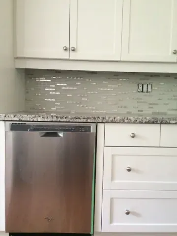 White kitchen cabinetry and a glass mosaic backsplash