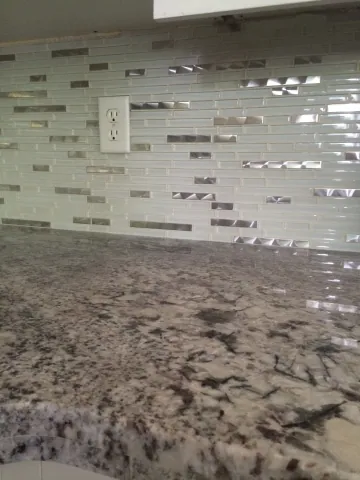 Glass mosaic backsplash above a stone kitchen countertop
