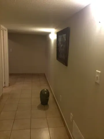 Tiled basement hallway with wall lighting