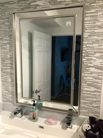 Vanity mirror framed by small mosaic wall tiles