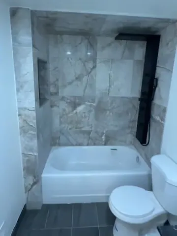 Grey marble-look tub surround with black shower fittings
