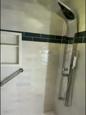 White shower tiles with a dark green accent band