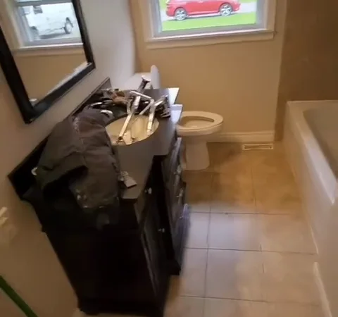Before renovation: dark bathroom vanity, framed mirror and beige floor tiles