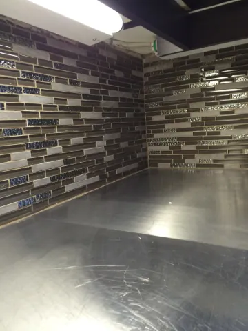Horizontal mosaic backsplash beneath dark kitchen cabinetry