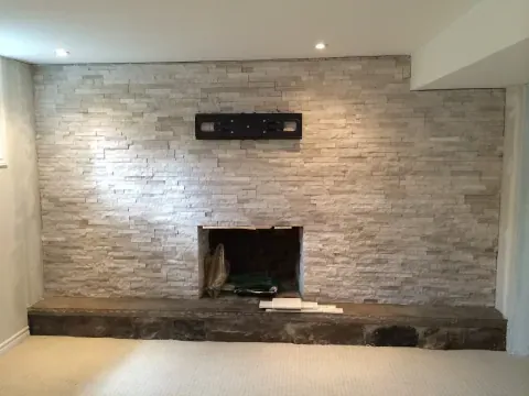 Stacked stone fireplace wall with recessed lighting