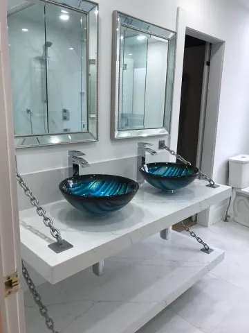 Double vanity with blue glass basins and illuminated mirrors