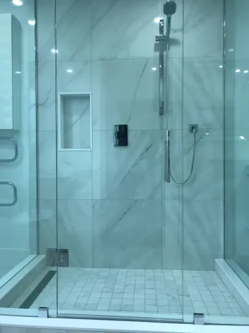 Glass shower enclosure with large marble-look wall tiles
