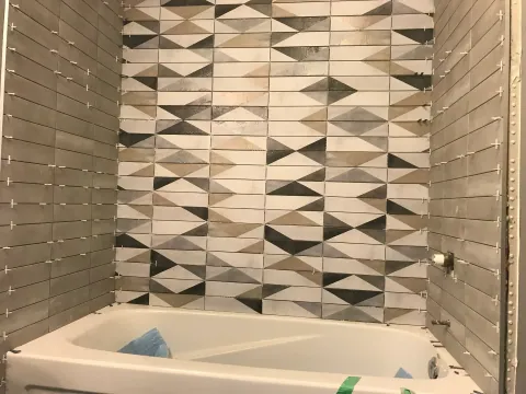 Geometric wall tile above a bathtub during installation