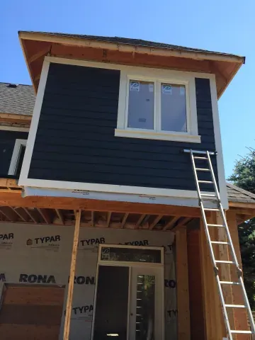 Dark siding and white window trim on the upper addition