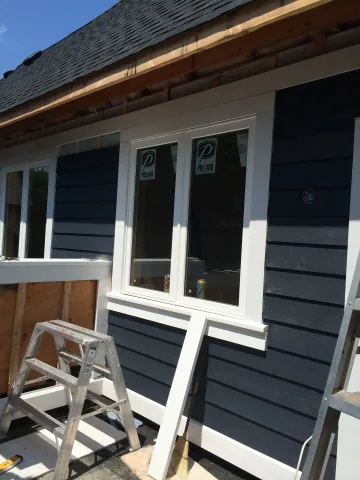 Exterior siding being fitted around a row of new windows