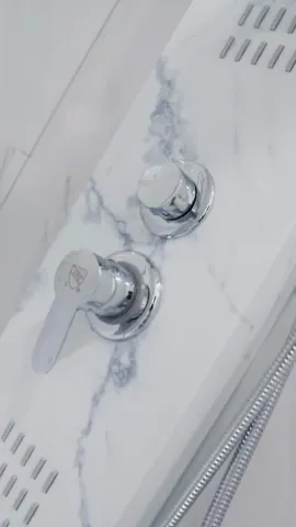 Chrome shower controls on a white marble-look shower panel