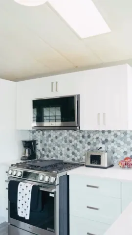 White kitchen cabinetry and a circular mosaic backsplash above the range