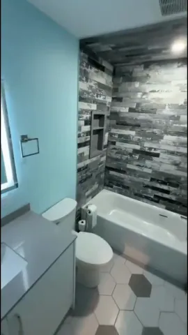Tiled bathtub surround and geometric floor tiles beside a white vanity