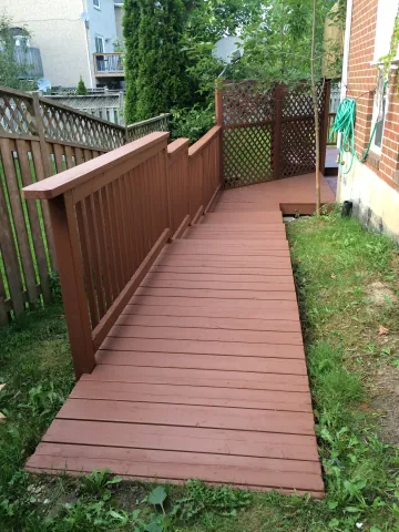 Timber walkway with railing beside a brick house