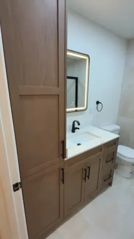 Timber bathroom vanity with a white countertop and illuminated mirror