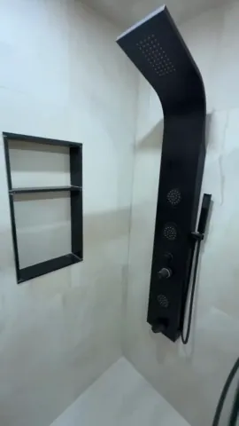 Black shower panel and recessed wall niche in a tiled shower