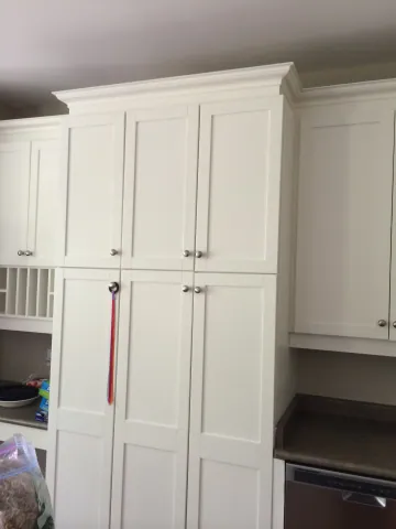 Full-height white kitchen cabinetry with crown moulding