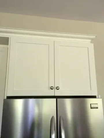 White cabinets above a stainless-steel refrigerator