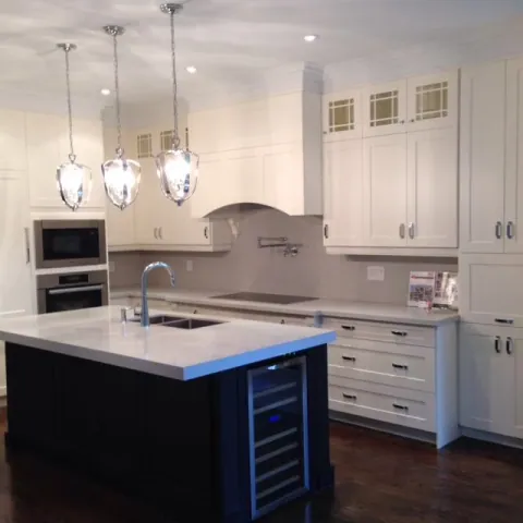 White kitchen cabinetry, a dark island and pendant lighting