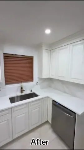 White kitchen cabinetry and sink beneath a window